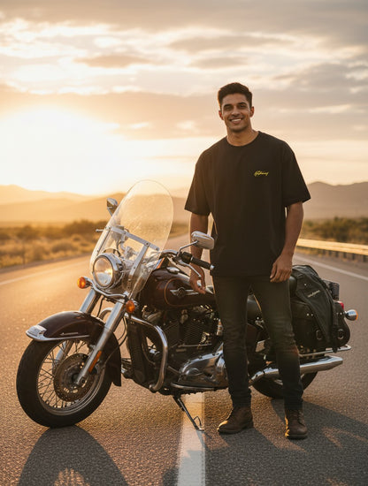 Print 999 black oversized cotton t-shirt worn by a man standing next to a motorcycle at sunset.