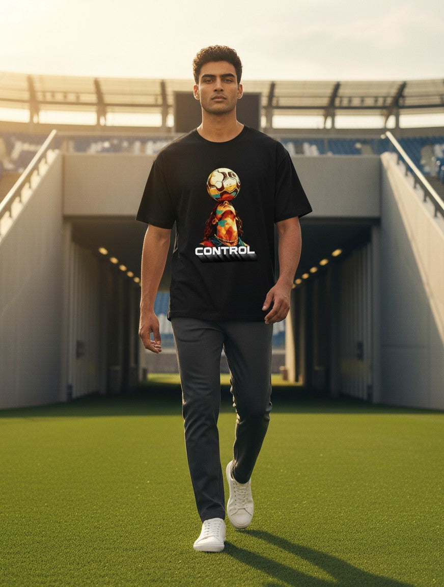 Print 999 black graphic t-shirt featuring a soccer player balancing a ball, worn by a man on a stadium pitch.