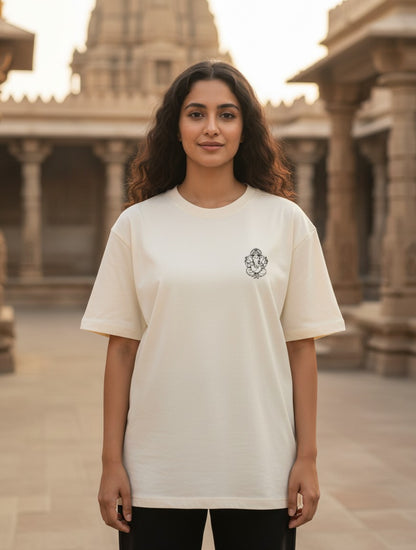 Woman wearing a Print 999 cream oversized cotton t-shirt with a small black Ganesha graphic at a temple