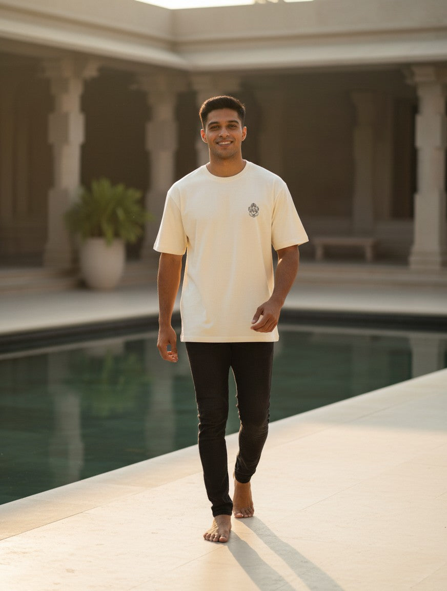 Print 999 unisex cream oversized heavyweight cotton t-shirt with Ganeshaji line art, worn by a man by a pool.