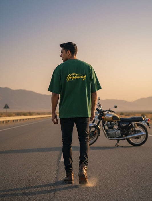 Print 999 green oversized cotton t-shirt with yellow Highway Rush graphic, worn by a man on a desert highway.