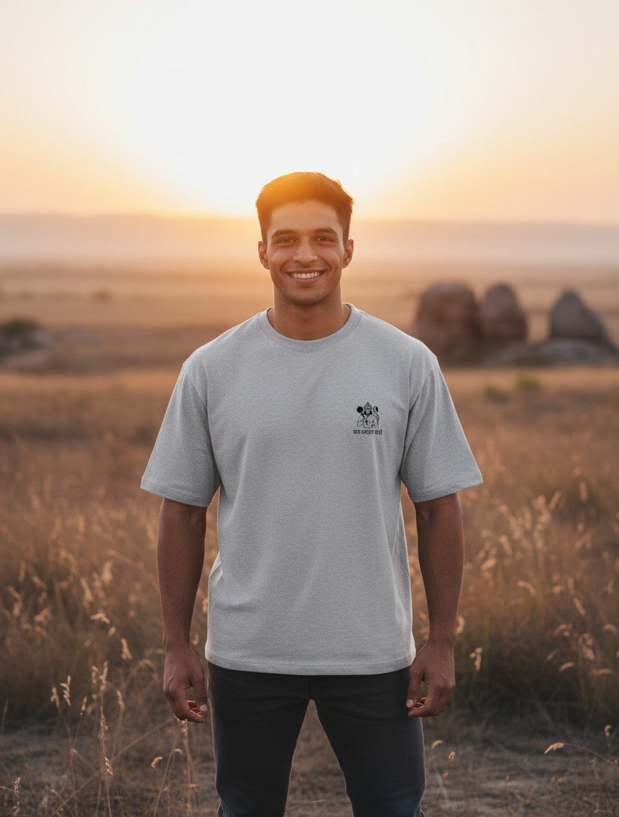 Print 999 grey oversized t-shirt with Hanuman Ji chest emblem worn by a smiling man in a field at sunset