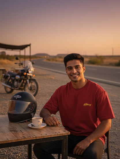 Print 999 Highway Rush oversized red cotton t-shirt worn by a man at a roadside cafe with a motorcycle and helmet.
