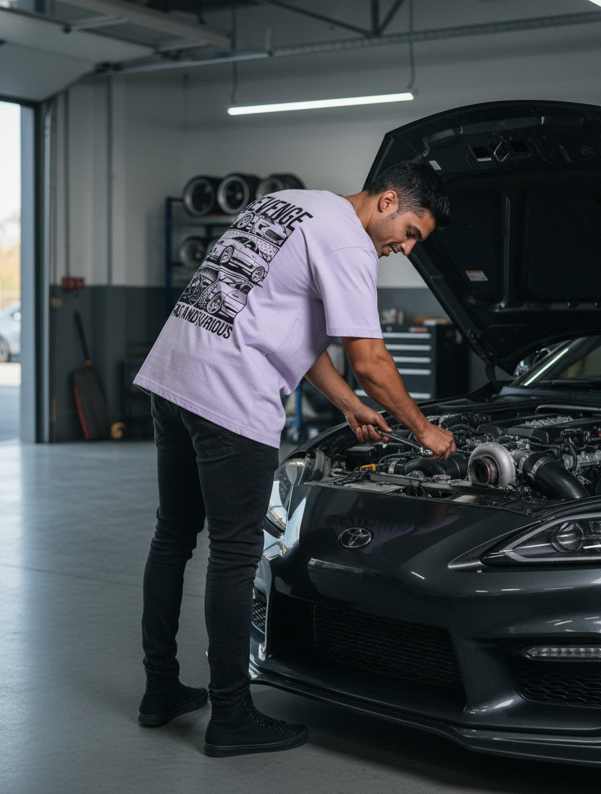 Print 999 light purple oversized cotton t-shirt with a street racer graphic on the back, worn by a man working on a car.