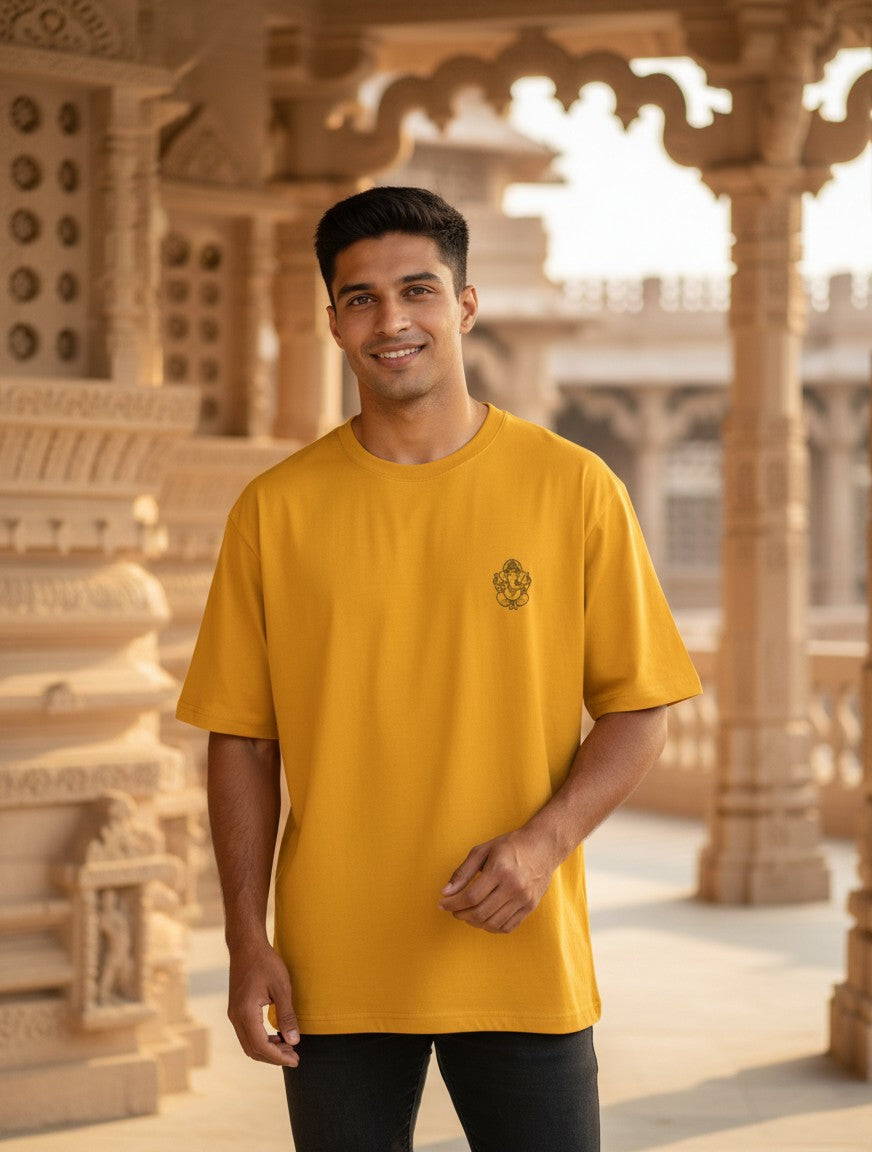 Print 999 mustard yellow oversized cotton t-shirt with a small Ganesha line art print, worn by a man in a temple.