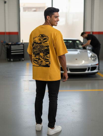 Print 999 mustard yellow oversized t-shirt with black automotive back graphic worn by a man in a garage.