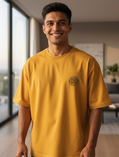 Print 999 mustard yellow oversized t-shirt with a small black embroidered Om Sri Yantra emblem on a smiling man.