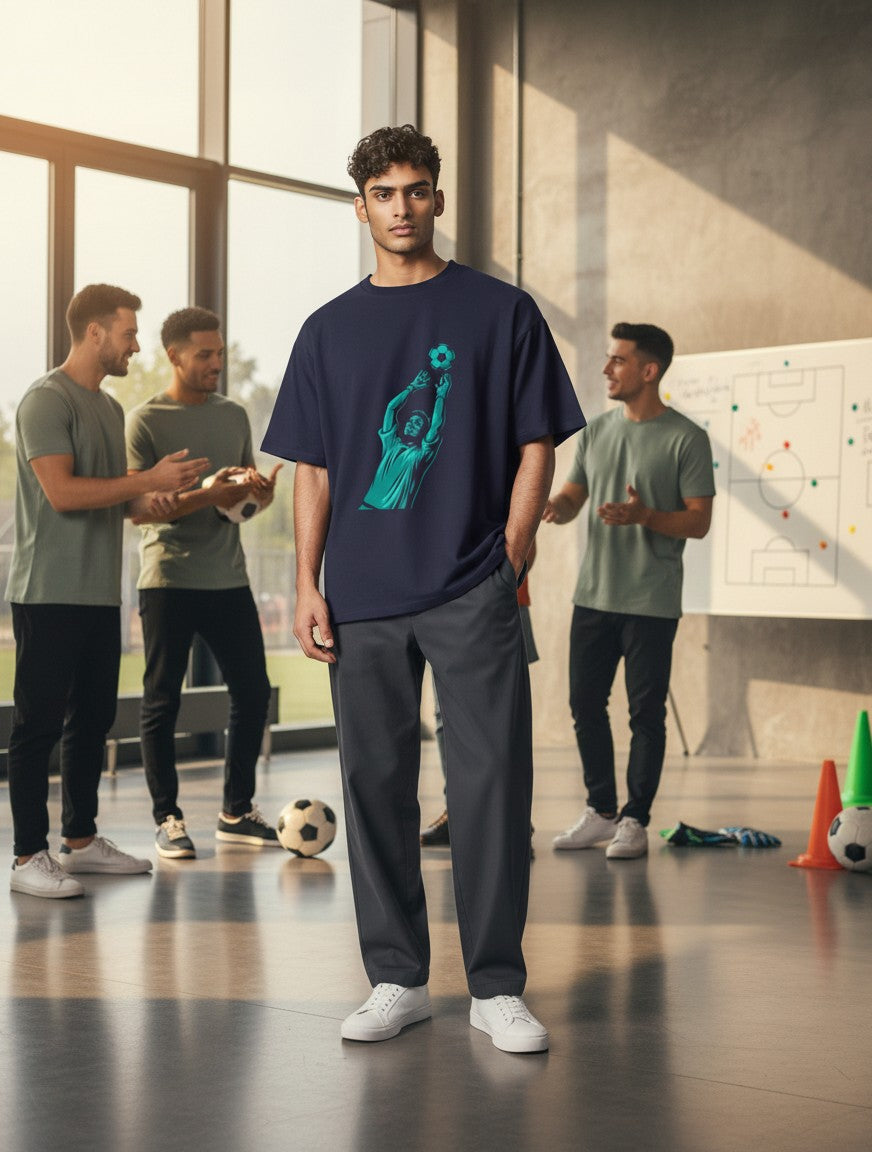 Print 999 navy blue graphic t-shirt with goalkeeper print worn by a man in a modern studio with teammates