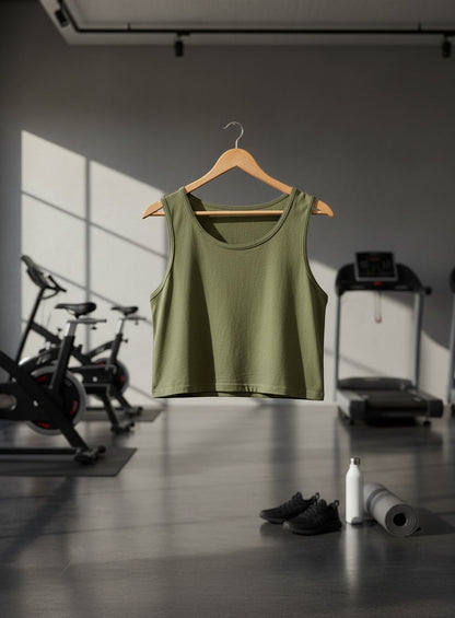 Print 999 olive green premium cotton crop tank top hanging on a wooden hanger in a gym setting.