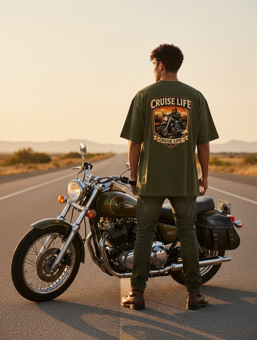 Print 999 olive green heavyweight cotton oversized t-shirt with motorcycle graphic on back, worn by man on a highway.