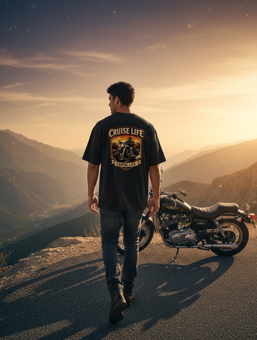 Print 999 oversized black cotton t-shirt with motorcycle graphic, worn by a man standing by a bike on a mountain road.
