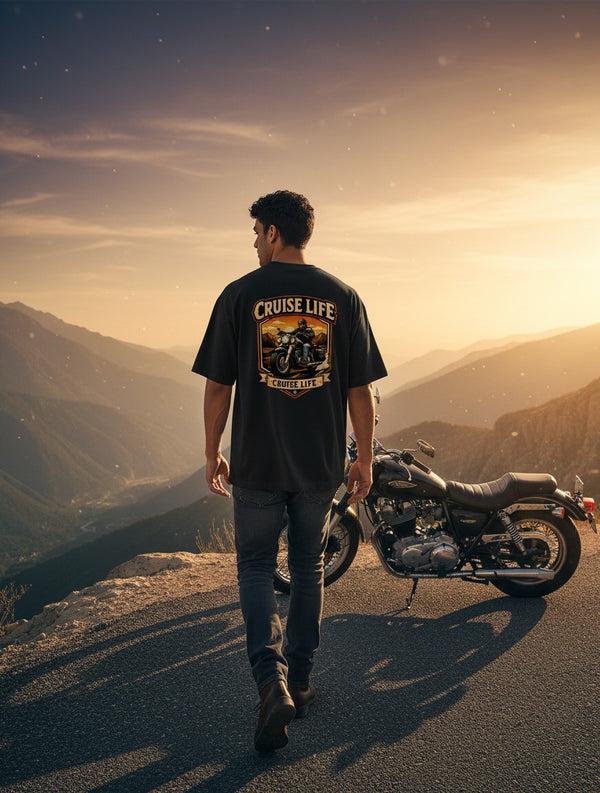 Print 999 oversized black cotton t-shirt with motorcycle graphic, worn by a man standing by a bike on a mountain road.