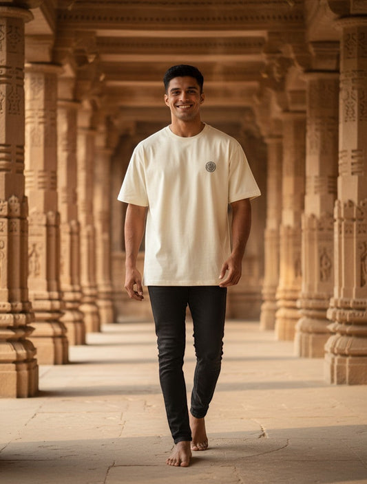 Print 999 oversized cream t-shirt with embroidered Sri Yantra emblem worn by a man in a temple corridor.