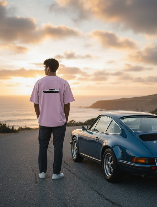 Print 999 oversized light pink t-shirt with car graphic on back, worn by a man standing by a blue vintage sports car.