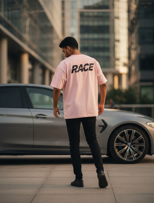 Print 999 light pink oversized t-shirt with RACE graphic on back, worn by a man standing next to a luxury car.