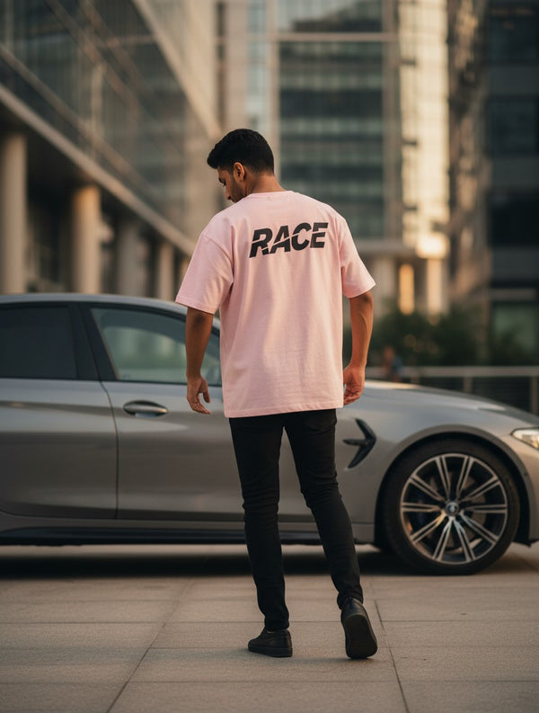 Print 999 light pink oversized t-shirt with RACE graphic on back, worn by a man standing next to a luxury car.