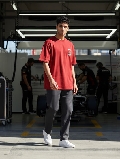 Print 999 red oversized cotton t-shirt with graphic print worn by a man in a racing garage setting