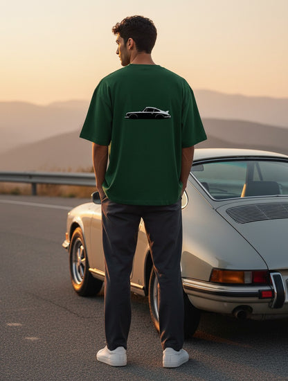 Print 999 Vintage Velocity oversized green t-shirt with a car graphic, worn by a man standing by a vintage car.