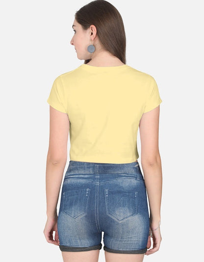 Print 999 pale yellow half-sleeve cotton crop top worn by a woman with blue denim shorts, back view